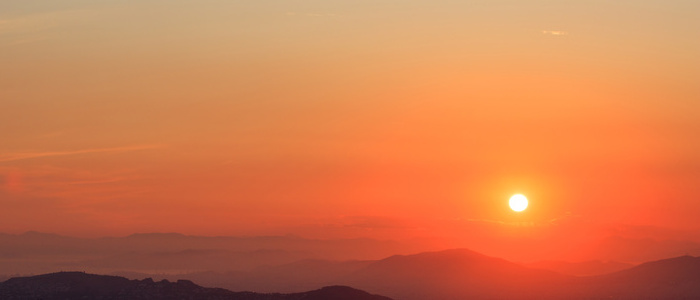 Beautiful sunset on sky over mountains background. The sun is on