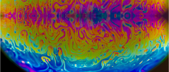Vivid rainbow colours of a Macro soap bubbles creating psychedelic patterns under light dome